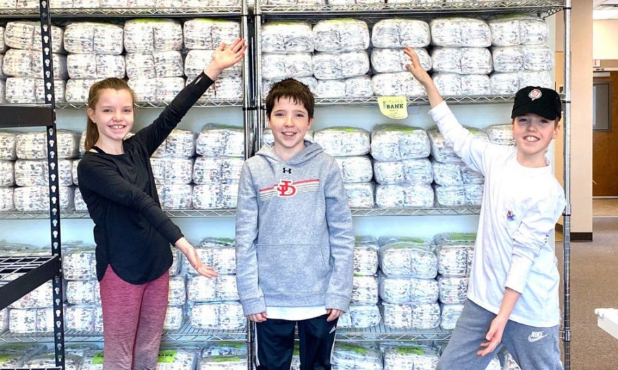 Young volunteers display the stocked supply of diapers to be donated.