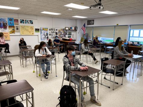 Students sit in the classroom social distanced and masked.