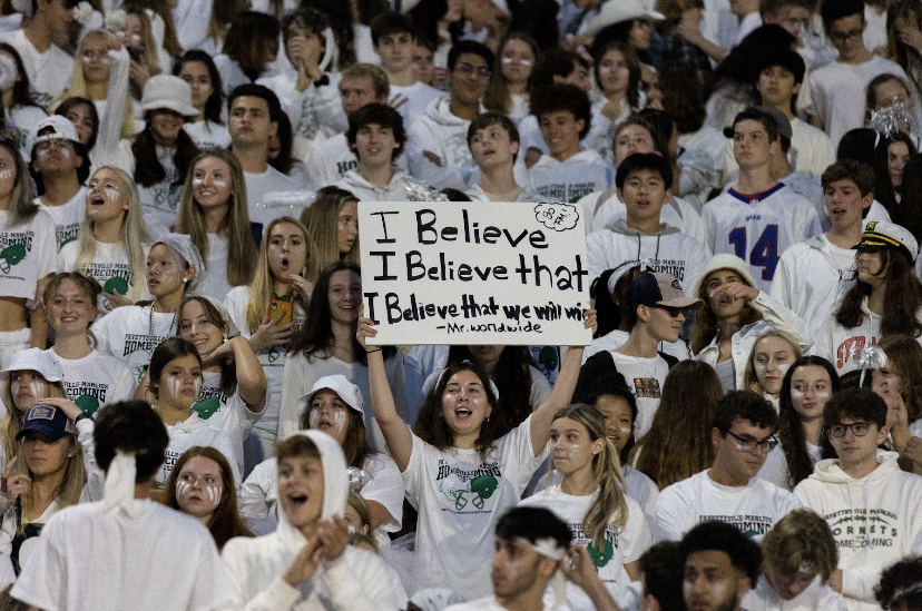 Students dressed all in white cheer on the football team from the stands.