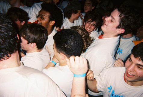 A group of students "mosh" in a tight group while dancing.