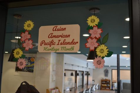 The FM High School library displays a AAPI sign with colorful flowers and pictures of prominent authors.