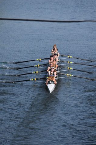 Members of the FM girls' eight person rowing team row in the water.