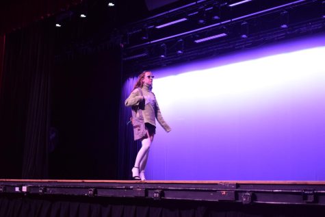 A student models her outfit--a gray sweater paired with a black skirt and white tights.