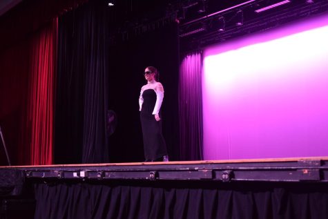 A student models her outfit--a black dress with white sleeves.