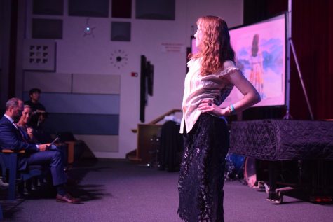 A student models her outfit--a white sleeveless top with black flowing pants.