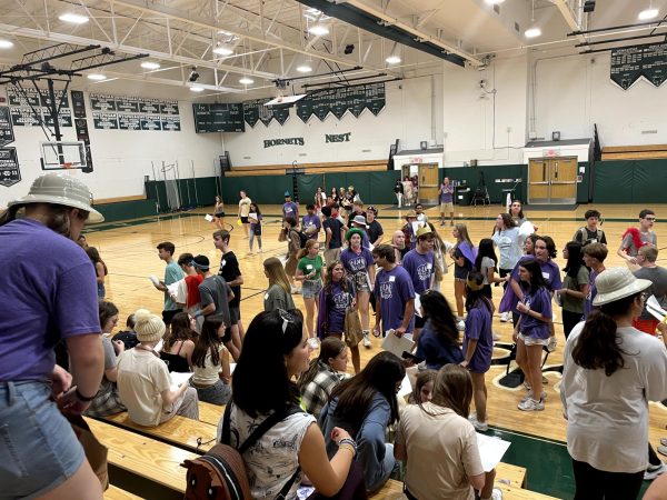 First year students wearing purple shirts arrive in the gymnasium.