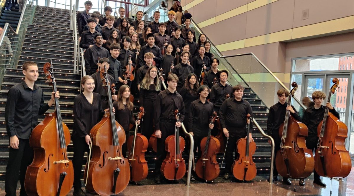 Members of the orchestra pose for a group photo with instruments.