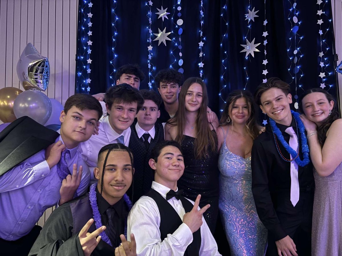 FM+students+are+dressed+in+formal+wear+in+front+of+the+decorated+backdrop+of+blue+with+silver+stars.