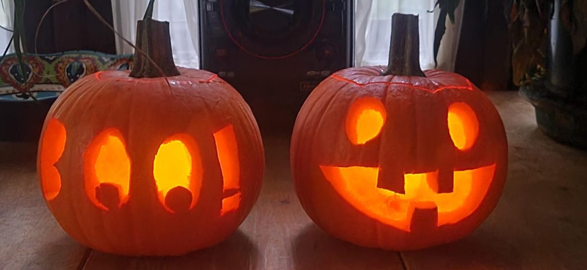 Carved pumpkins are lit inside, revealing a smiley face for one, and a Boo carved into the second.