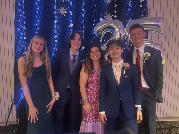 The junior class officers pose with teacher Kari Hammond at the prom location in front of the blue and silver backdrop.