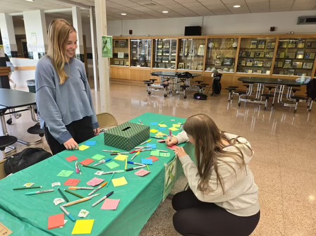 A student signs up for the club at a table set up in the high school foyer.