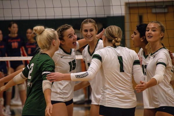 FM players on the court huddle together to celebrate.