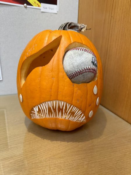 The pumpkin has a baseball inserted where an eye would be. It has spiked teeth in the mouth opening.