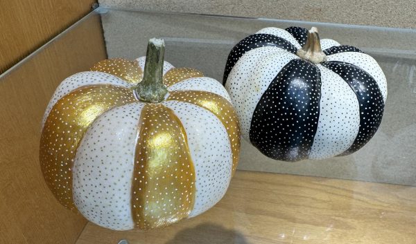 Two pumpkins--one gold and white, the other black and white are decorated with polka dots.