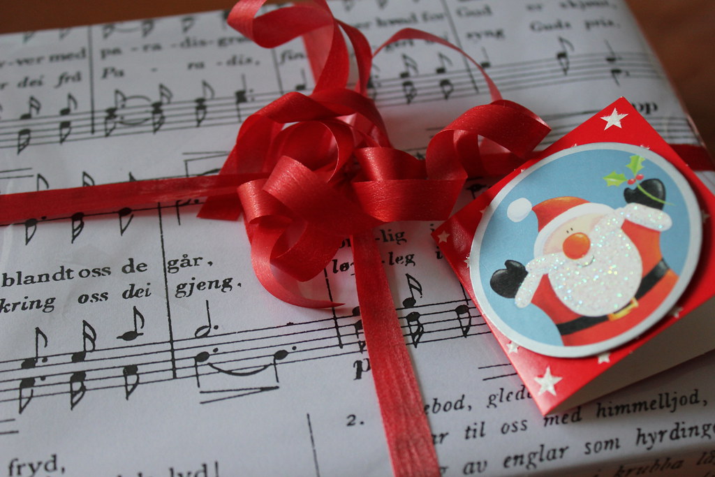 Sheet music is wrapped with a red ribbon and a Santa card.