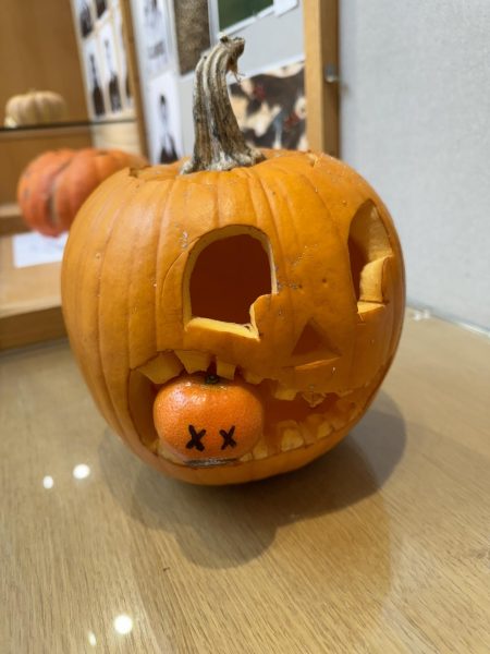 This pumpkin has a tangerine inserted into its mouth opening.