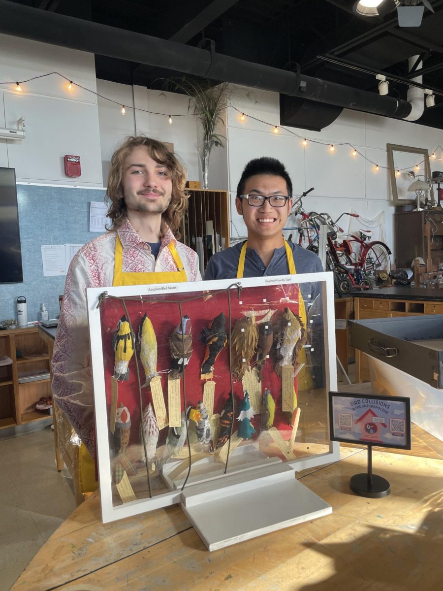 Students pose in front of a felt bird creation.