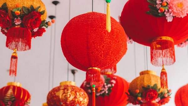 A variety of red lanterns, adorned with floral arrangements, hang against a light background.