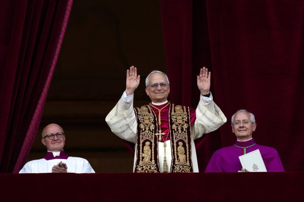 Pope Leo XIV waves to the crowd wearing the burgundy and gold vestments of the pope-elect.