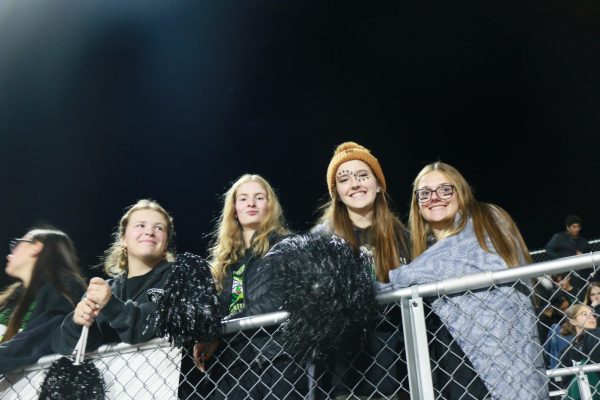 A group of female students stands at the fence.