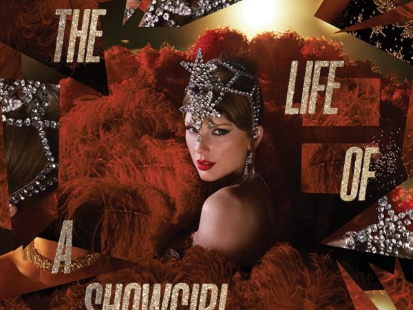The cover shows the title of the album in glittering gold. Swift is dressed as a show girl, surrounded by maroon feathers. She has a headdress on with glittering stars in front.