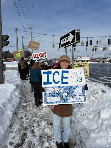 Geng stands at the protest site with an anti-ICE poster.