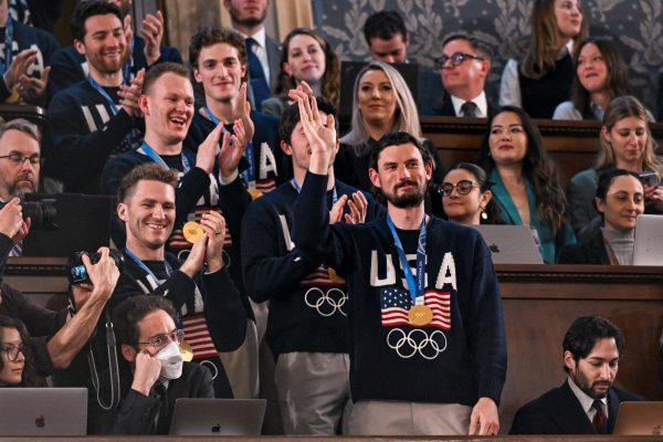 Members of the team stand at the address from the balcony and wave to the crowd, wearing their gold medals.