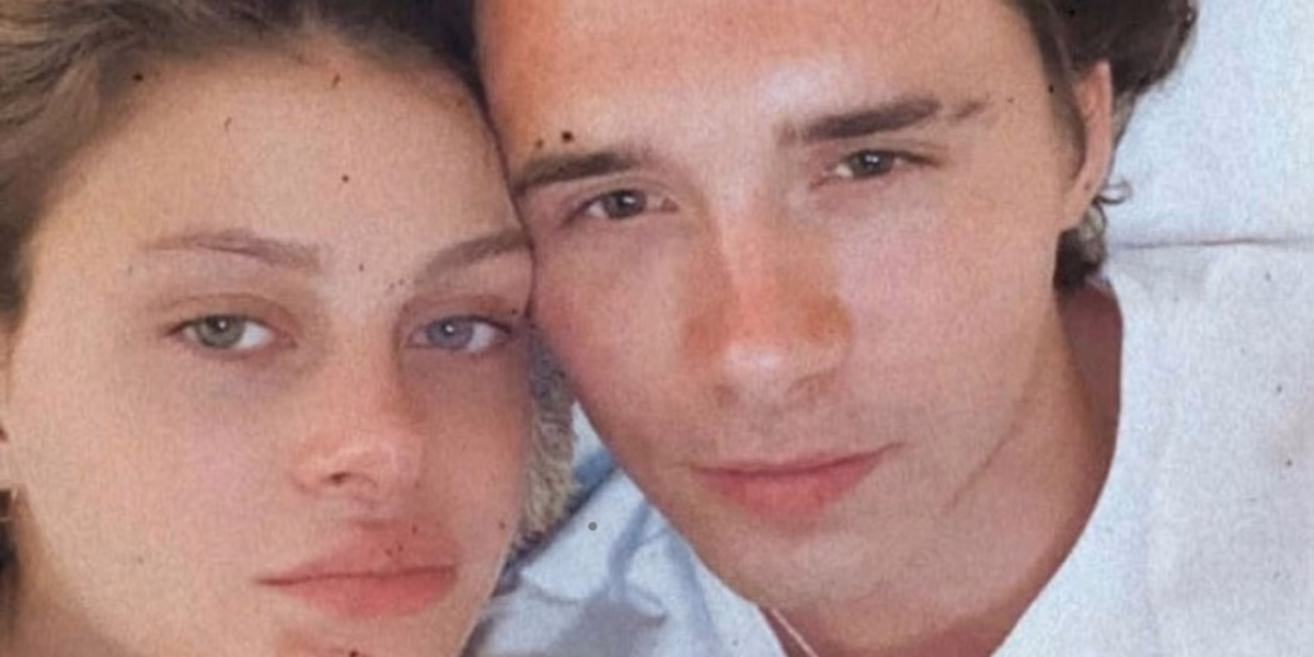 The image shows an extreme close up of the couple with their heads pressed together facing the camera with serious expressions.