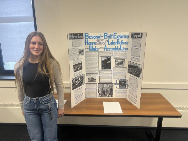 The student stands with her project.