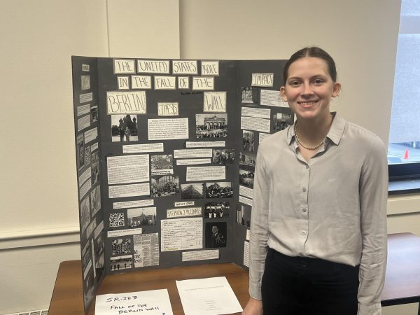 The student stands with her project.