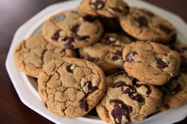 Chocolate chip cookies sit on a white plate